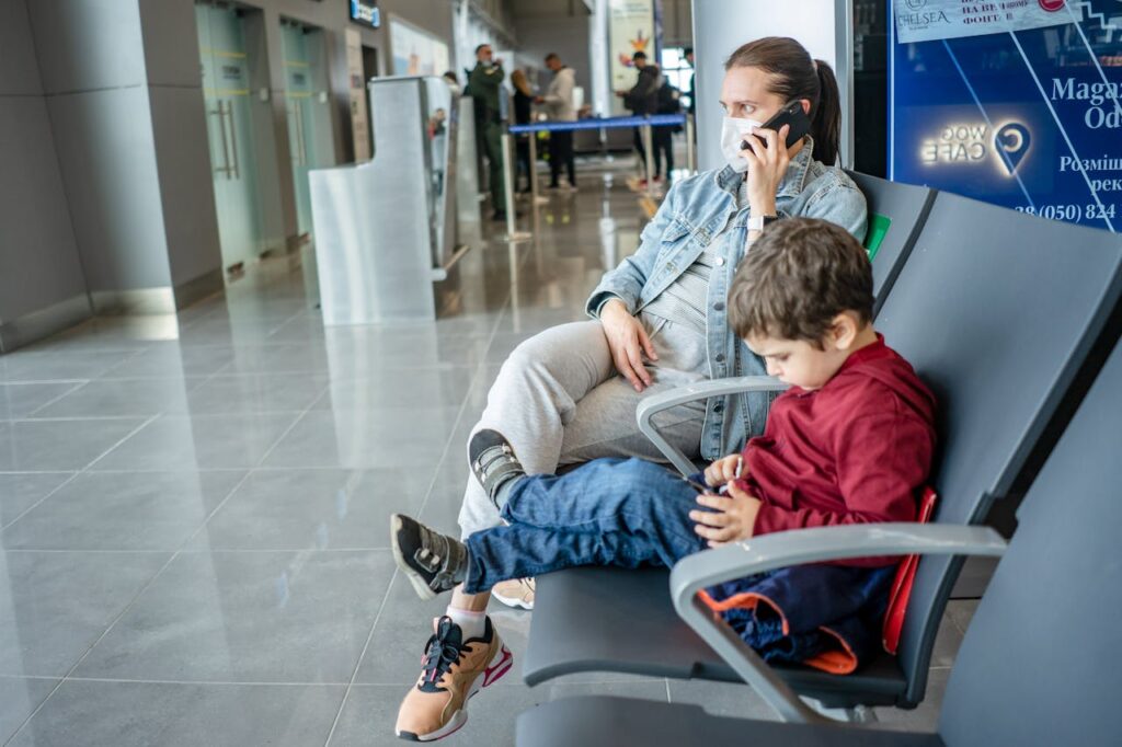 Mãe e filho sentados em banco no aeroporto, esperando o voo